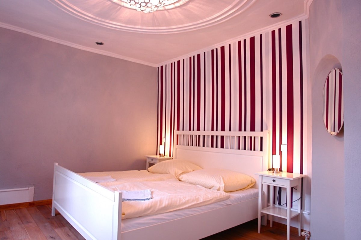 Double room with a white bed and a striped feature wall
